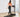 A woman in a pink sports bra and black leggings walks on a treadmill