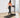 A woman in a pink sports bra and black leggings walks on a treadmill
