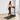A woman in a pink sports bra and black leggings walks on a treadmill
